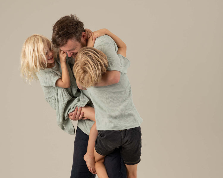 Vater und Kinder haben Spaß im Partnerlook aus mintfarbenem Musselin