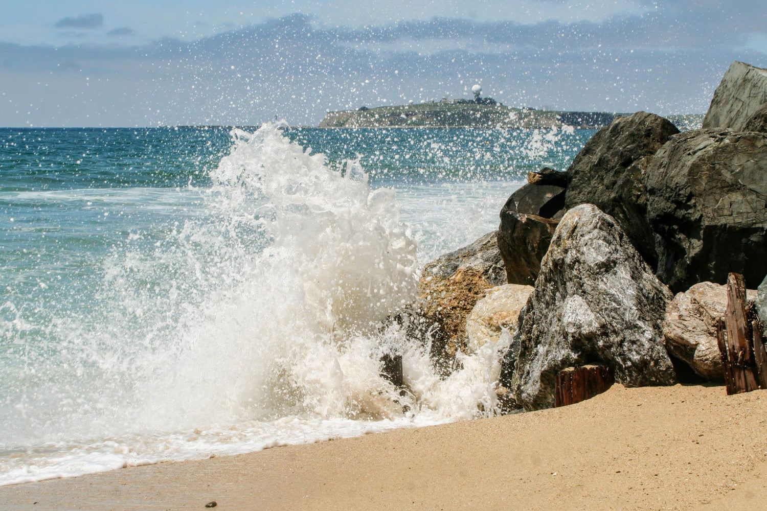 Meer bricht sich am Felsen beim Strand. 