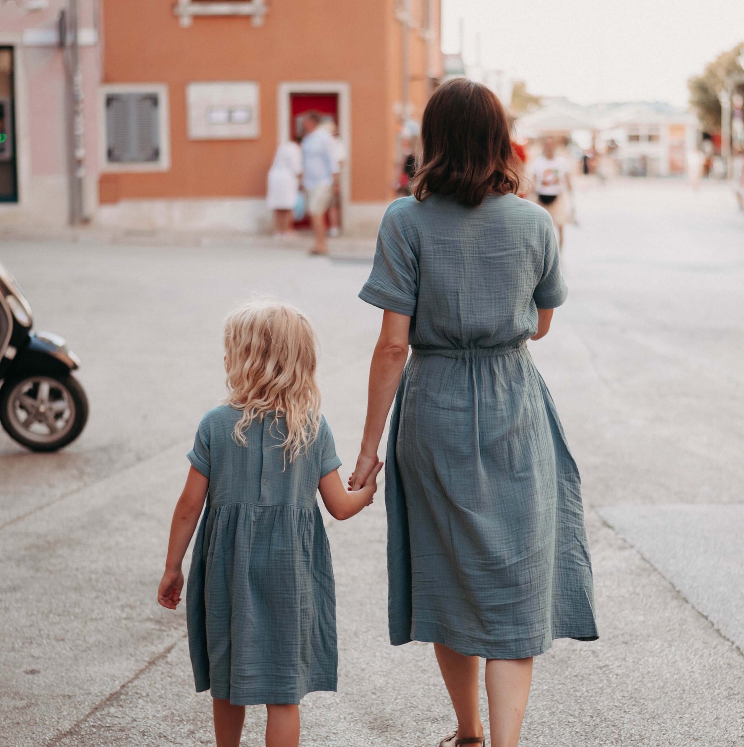 Mutter und Tochter im petrolfarbenen Partnerlook Hand in Hand auf der Straße