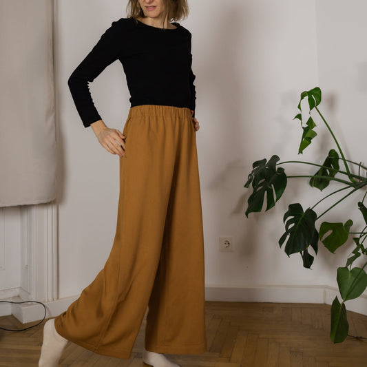 Frau in langer Hose mit weiten Beinen aus Tencel in der Farbe Senf Mustard; Urheber: Mini & Eve