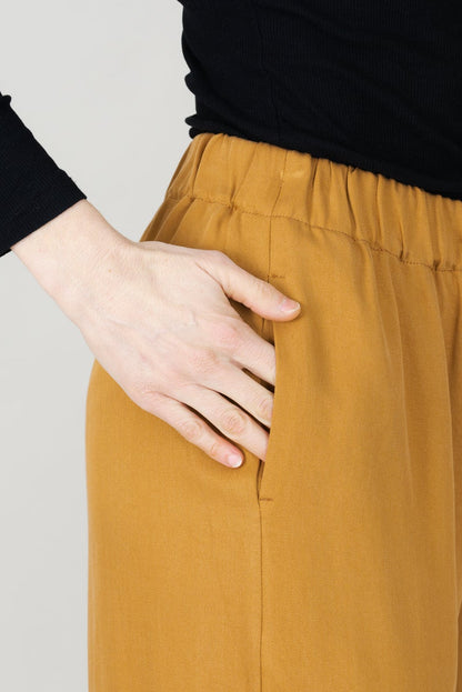 Frau in Tencel-Hose in der Farbe Senf mit Taschen; Urheber: Mini & Eve