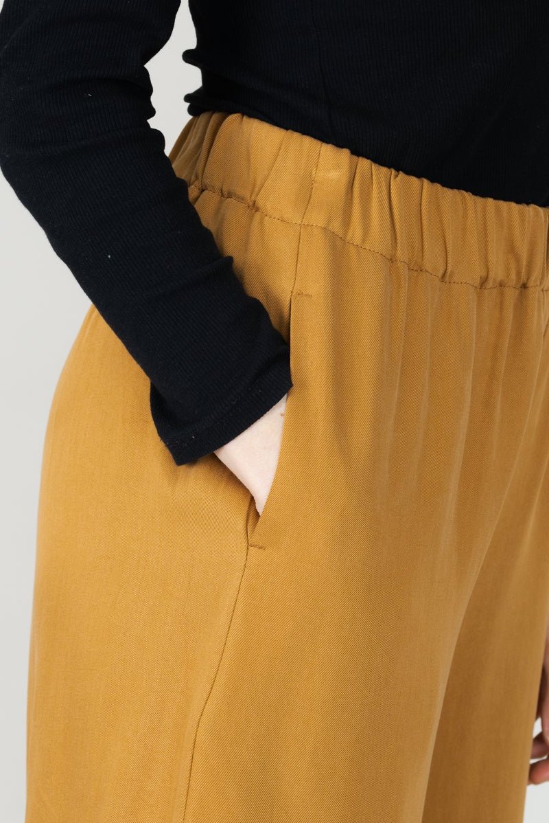 Frau in Tencel-Hose in der Farbe Senf mit Taschen; Urheber: Mini & Eve