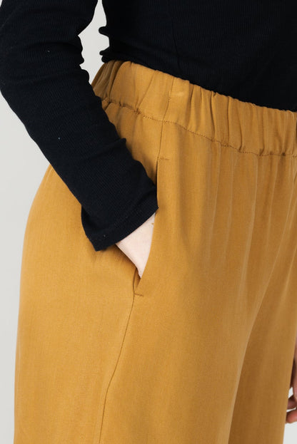 Frau in Tencel-Hose in der Farbe Senf mit Taschen; Urheber: Mini & Eve