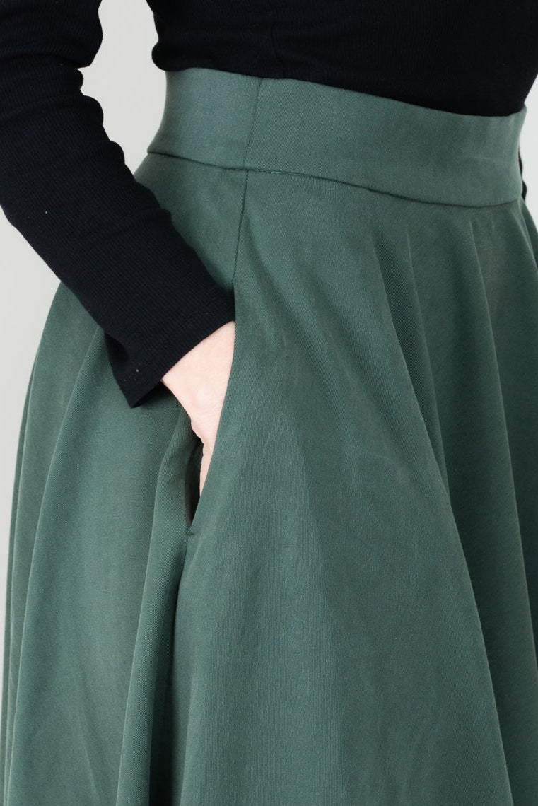 Frau in Tencel-Tellerrock in der Farbe Kiefer Dunkelgrün mit Taschen; Urheber: Mini & Eve
