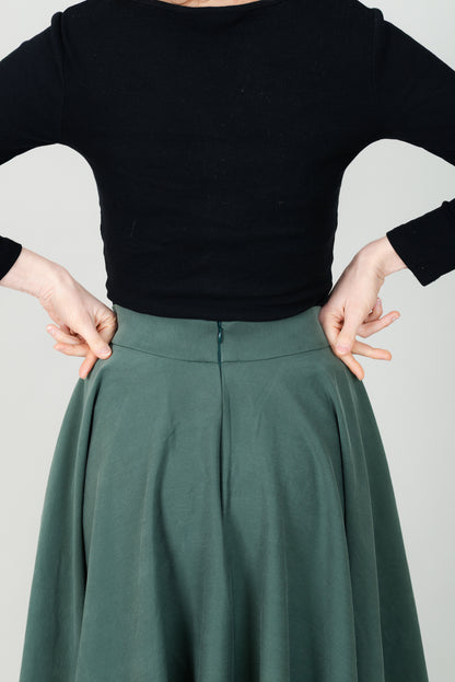 Frau in Tencel-Tellerrock in der Farbe Kiefer Dunkelgrün mit Taschen; Urheber: Mini & Eve