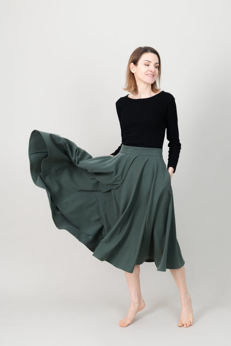 Frau in Tencel-Tellerrock in der Farbe Kiefer Dunkelgrün mit Taschen; Urheber: Mini & Eve