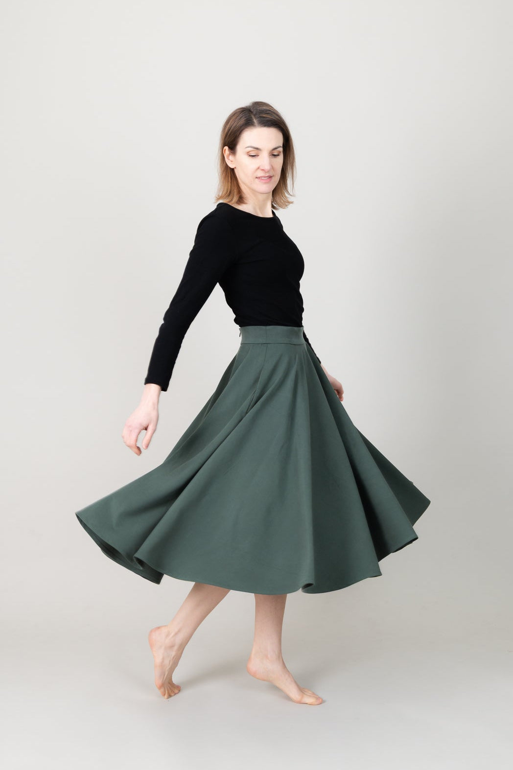 Frau in Tencel-Tellerrock in der Farbe Kiefer Dunkelgrün mit Taschen; Urheber: Mini & Eve