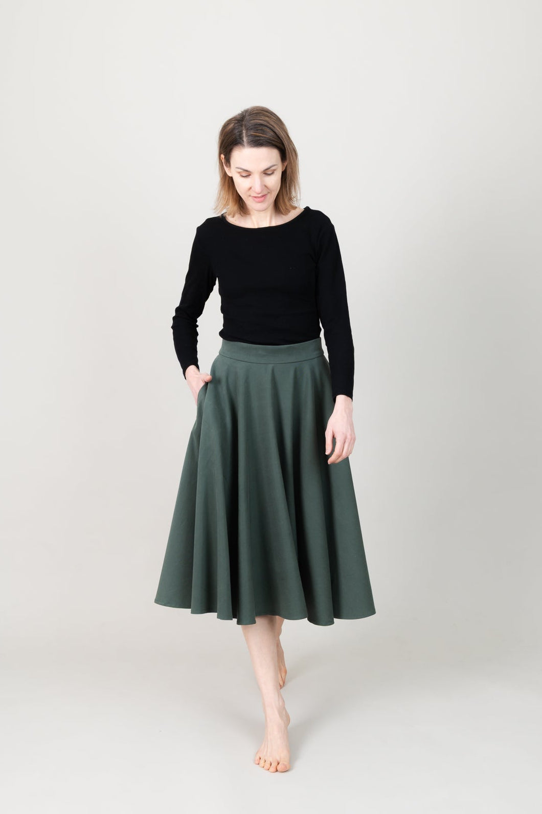 Frau in Tencel-Tellerrock in der Farbe Kiefer Dunkelgrün mit Taschen; Urheber: Mini & Eve