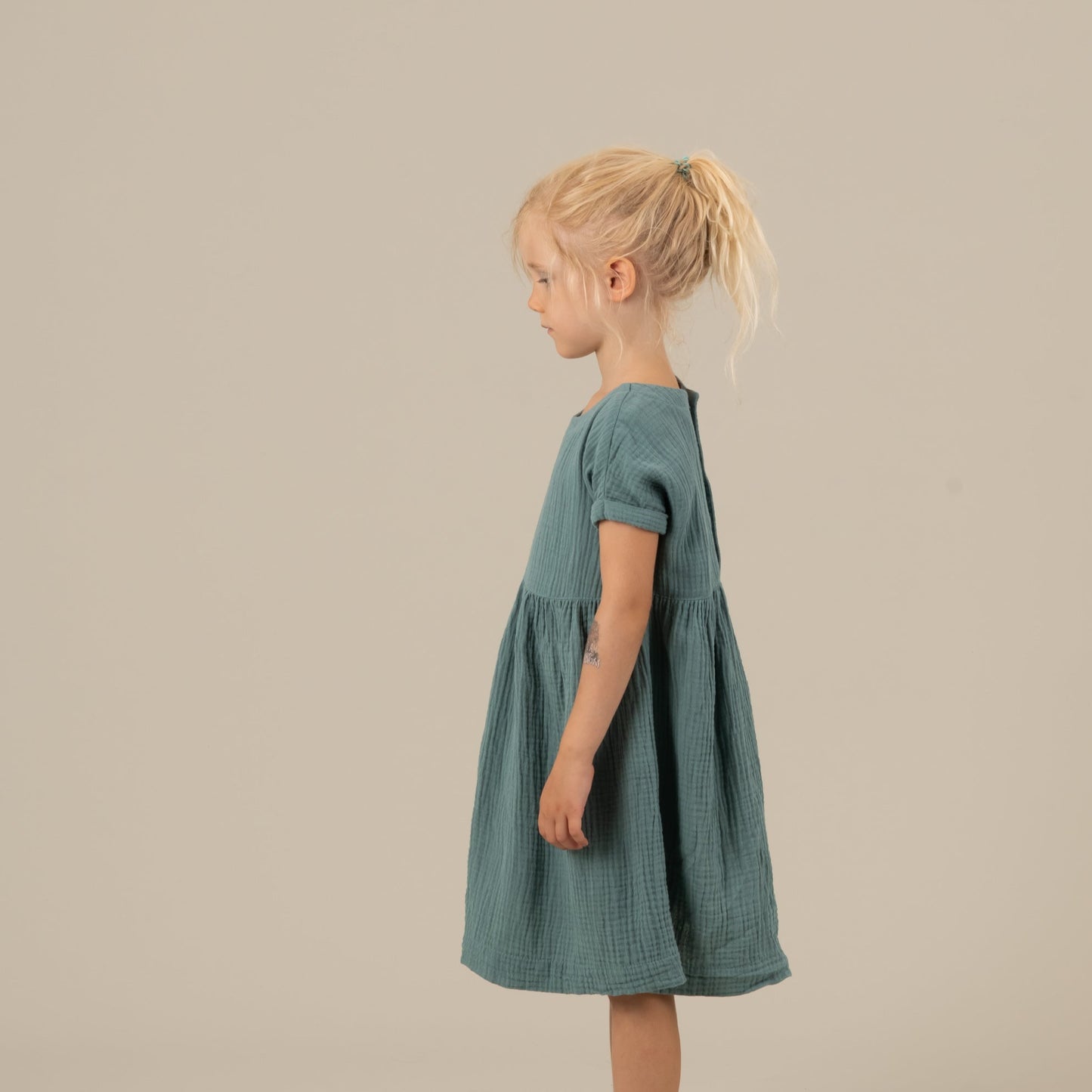 MIA Kinderkleid Musselin Petrol Seitenansicht links, Urheber: Mini & Eve